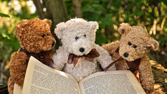 Photo of three stuffed animals reading a book.