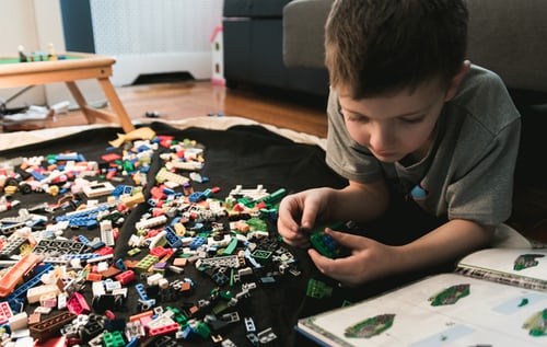 A boy lies on the floor playing with LEGOs.
